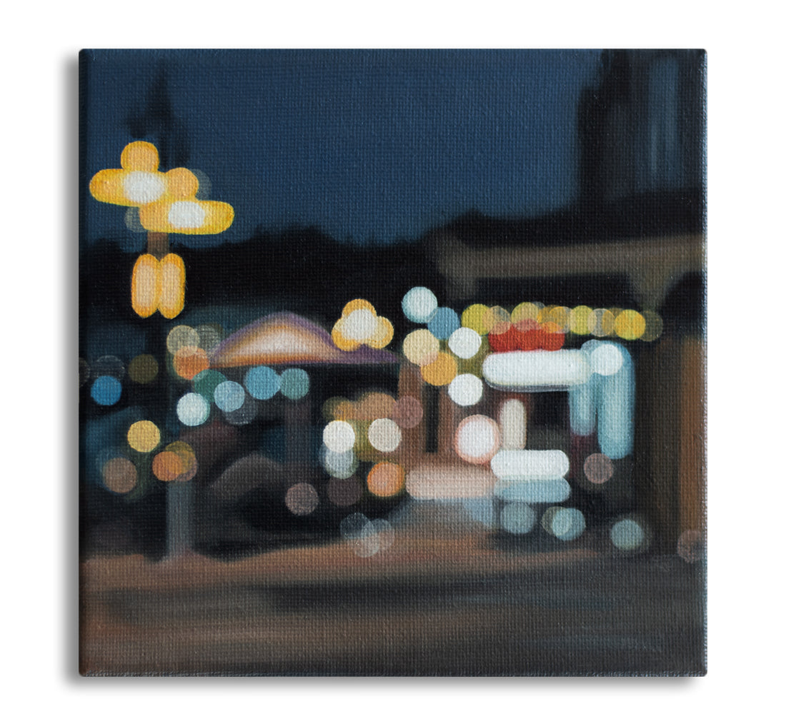 Wanaka New Zealand, lakefront drive cafe. Painted in a blurry bokeh style on a small canvas framed in wood frame. Lights of the street and stores. Art by New Zealand artist Mel McKenzie, The Penny Drops.