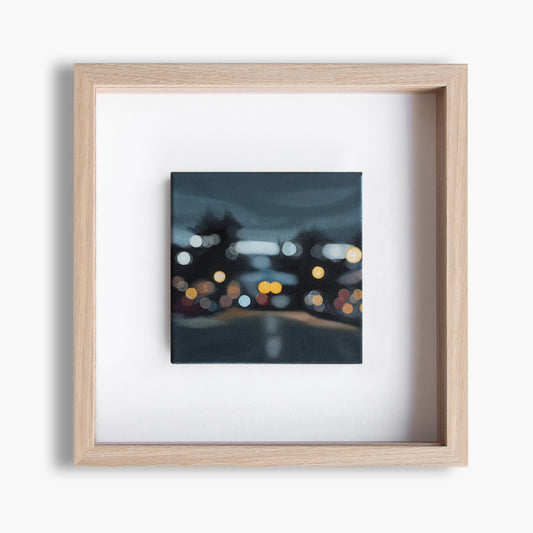 Wanaka New Zealand, Helmore street view towards lake. Painted in a blurry bokeh style on a small canvas framed in wood frame. Lights of the street and cars. Art by New Zealand artist Mel McKenzie, The Penny Drops.