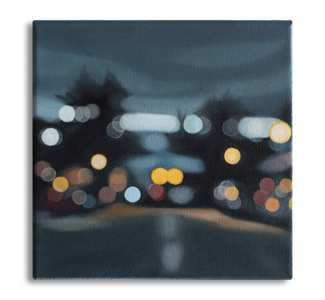Wanaka New Zealand, Helmore street view towards lake. Painted in a blurry bokeh style on a small canvas framed in wood frame. Lights of the street and cars. Art by New Zealand artist Mel McKenzie, The Penny Drops.