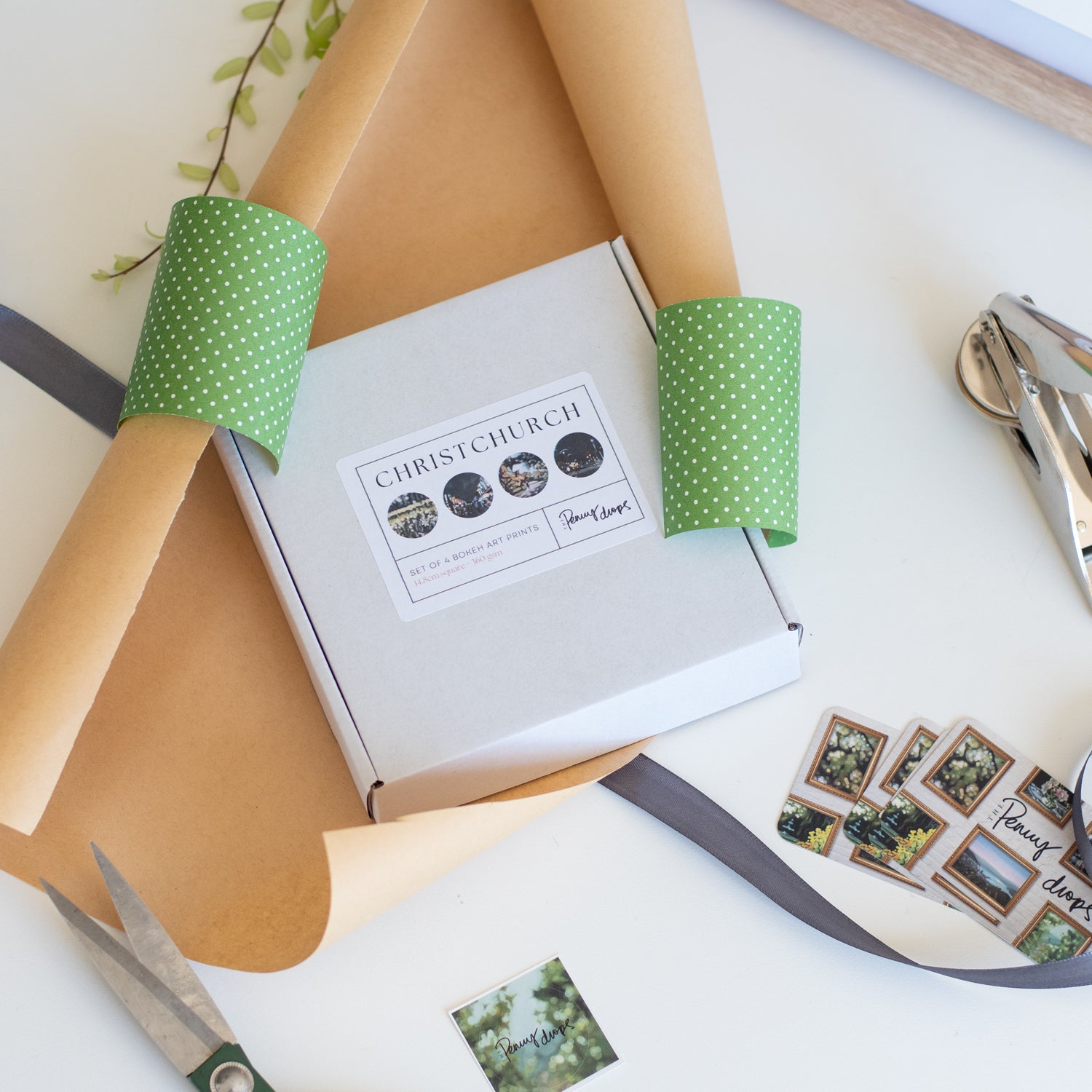 Box with green polka dot paper and Christchurch label on a white surface with stationery items.