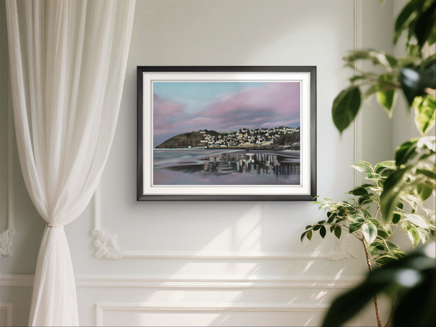 Framed artwork of a blurry bokeh coastal scene (St Clair Beach, Dunedin) on a wall with white curtains and a plant.