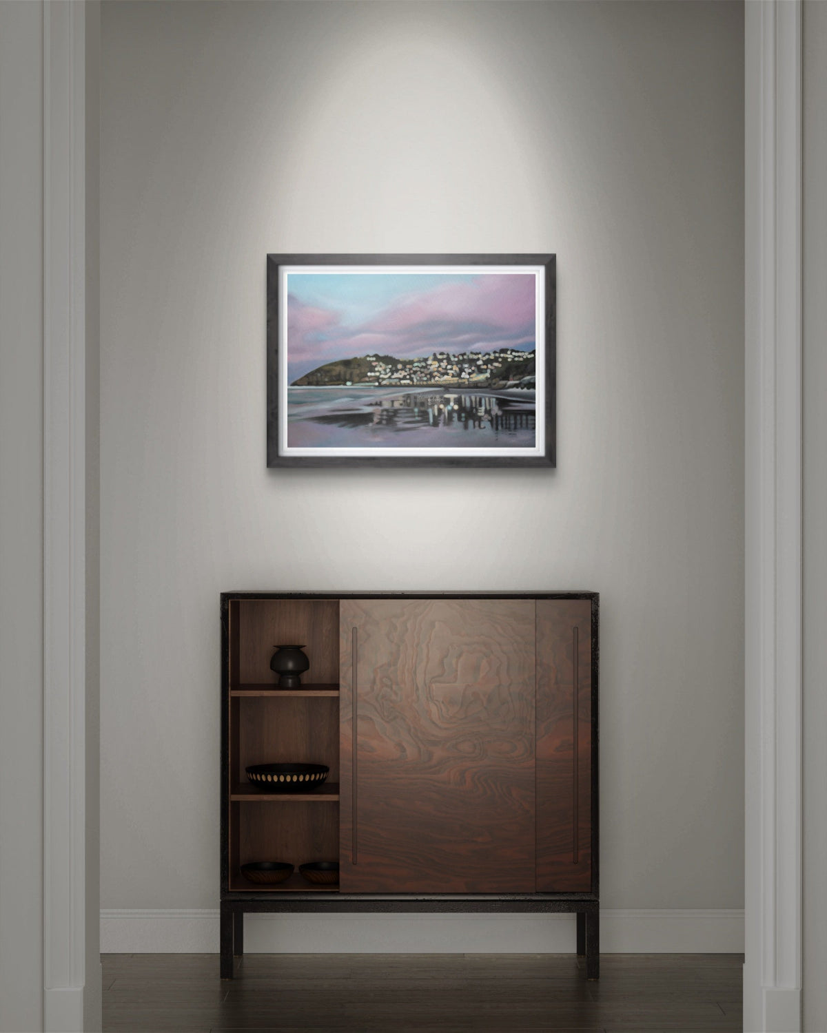 Framed St Clair Beach, Dunedin with pink toned sunrise skies and reflections on wet sand, fine art print artwork on a wall above a wooden cabinet.
