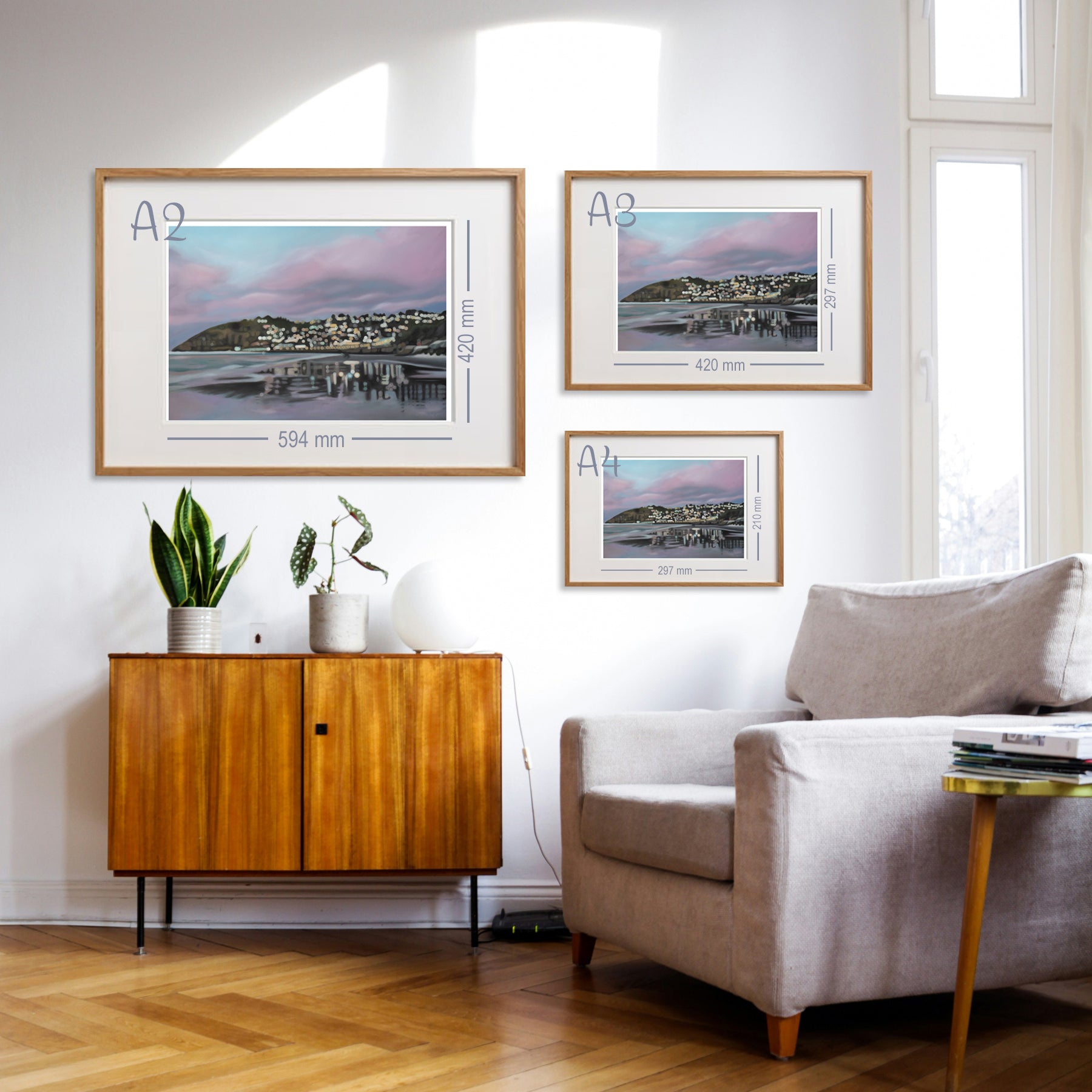 Living room with sizing suggestions of framed fine art prints of St Clair Beach, Dunedin, on the wall, wooden cabinet, and sofa.