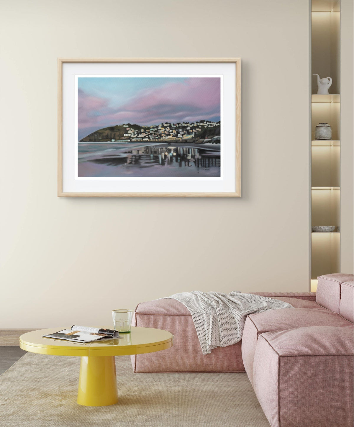 Framed St Clair Beach, Dunedin with pink toned sunrise skies and reflections on wet sand, fine art print artwork on a wall above a pink sofa and yellow table in a living room.